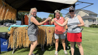 Women golfers enjoy drinks at a tiki-themed stand during the Wright County Golf Tournament.