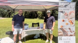 Two Buffalo Chiropractic Clinic representatives stand at a sponsor tent with informational displays during the Community Health Foundation of Wright County Golf Tournament.