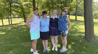 Four golf tournament participants pose under shaded trees along the course during the Community Health Foundation of Wright County Golf Tournament in Buffalo, Minnesota.