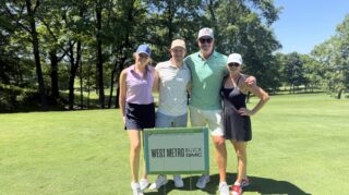 Four golf tournament participants pose on the course behind a West Metro Buick GMC sponsor sign during the Community Health Foundation of Wright County Golf Tournament in Buffalo, Minnesota.