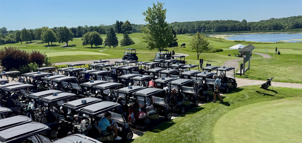 Rows of golf carts lined up at a golf course beside a lake during the Community Health Foundation of Wright County Golf Tournament in Buffalo, Minnesota.